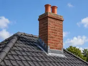 Brick chimney stack on a tiled roof requiring chimney repair and repointing
